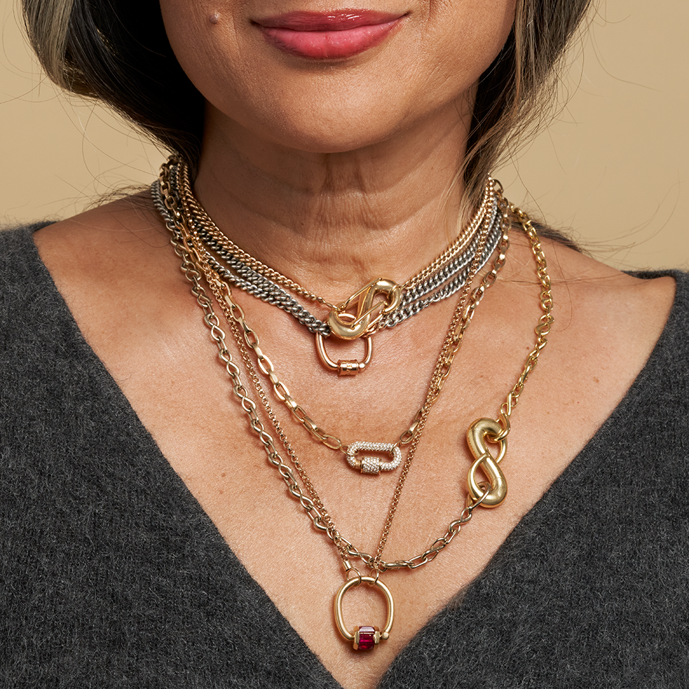 Close up of women's decolletage with many necklaces including biker chain necklace