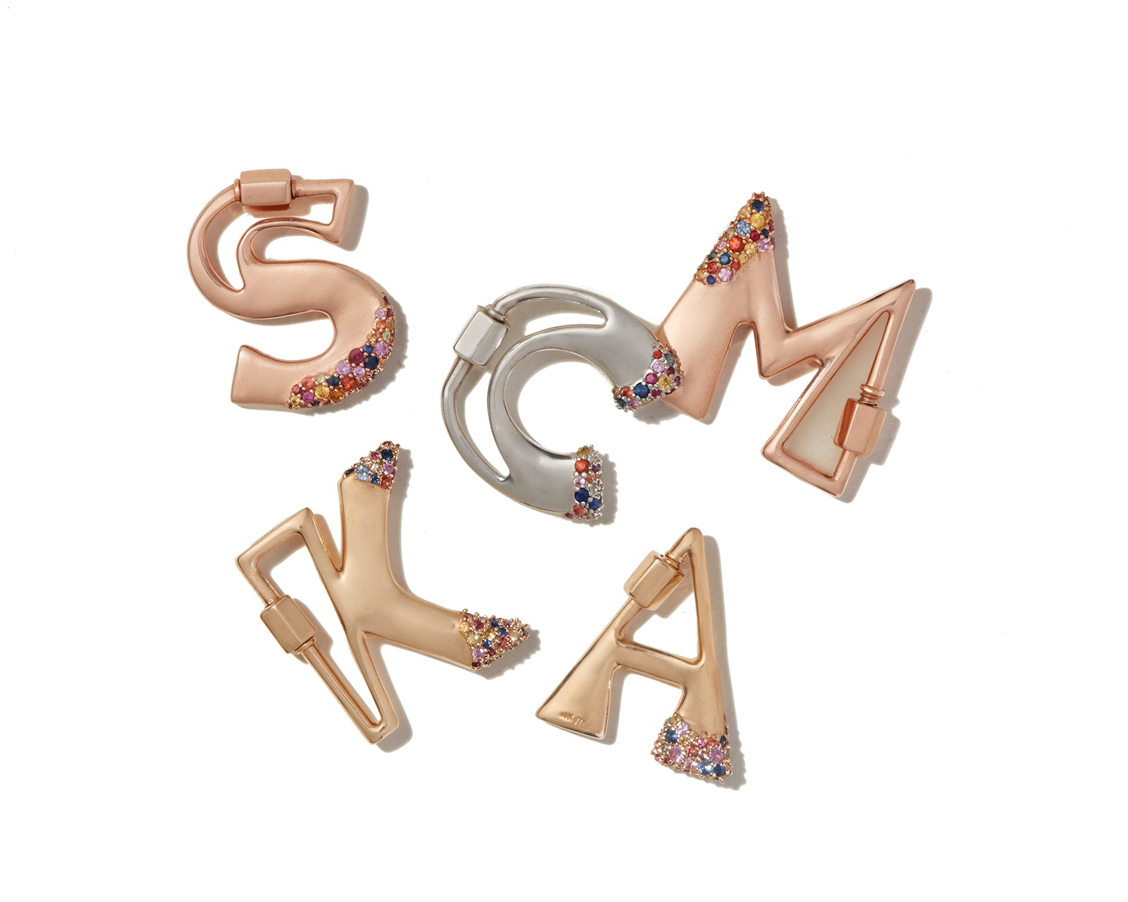 Mixed metal letter charms with colorful gemstones against white backdrop