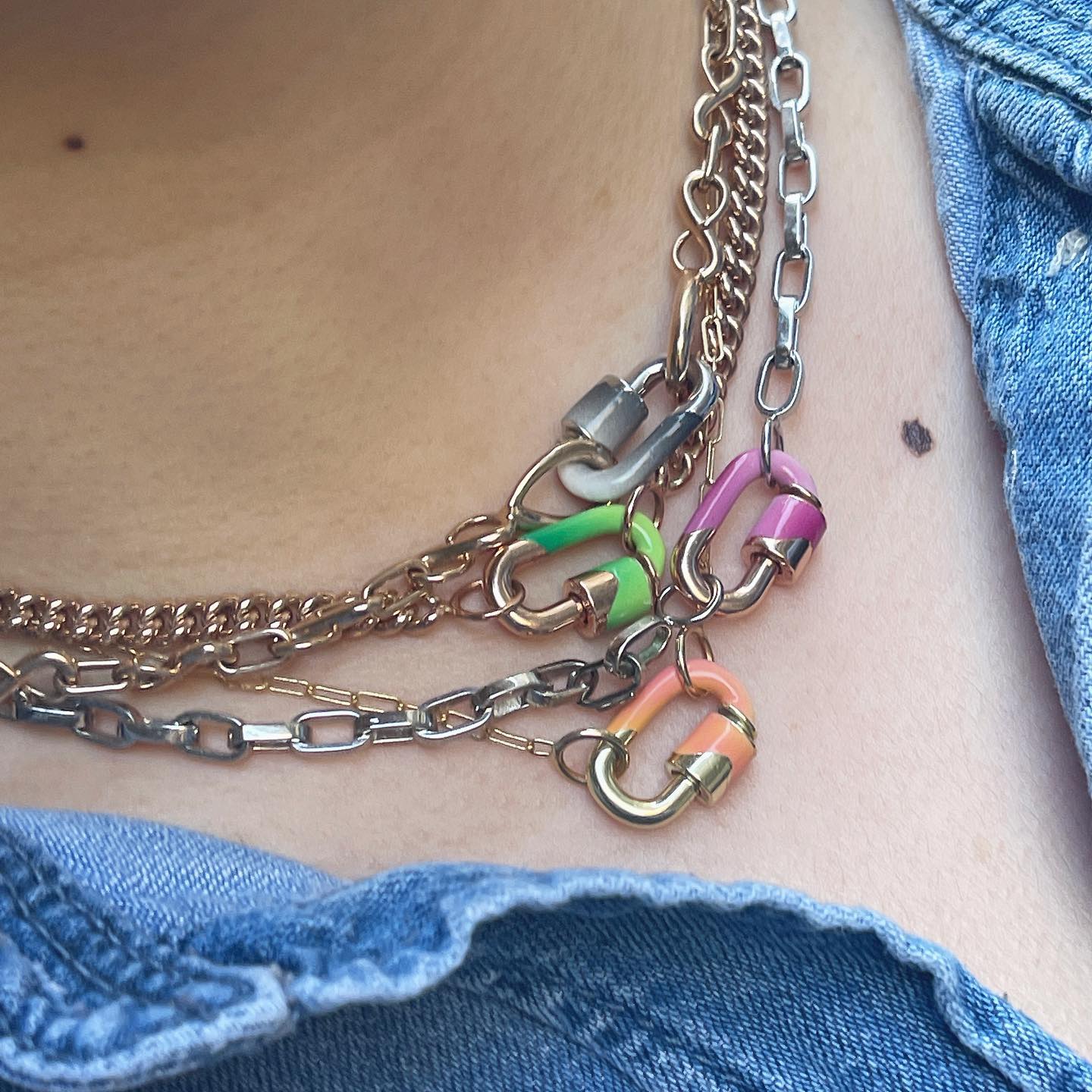 Close up of woman's decolletage wearing necklace with orange enamel jewelry lock