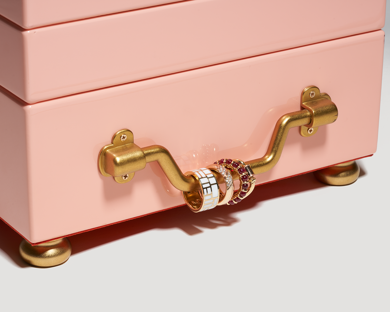 Close up of side handle on pink jewelry box with multiple rings attached