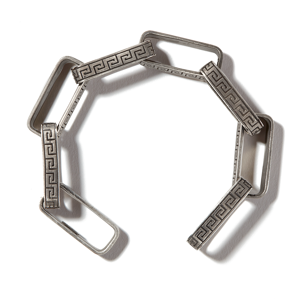 Silver greek key chain bracelet in circular shape against white backdrop