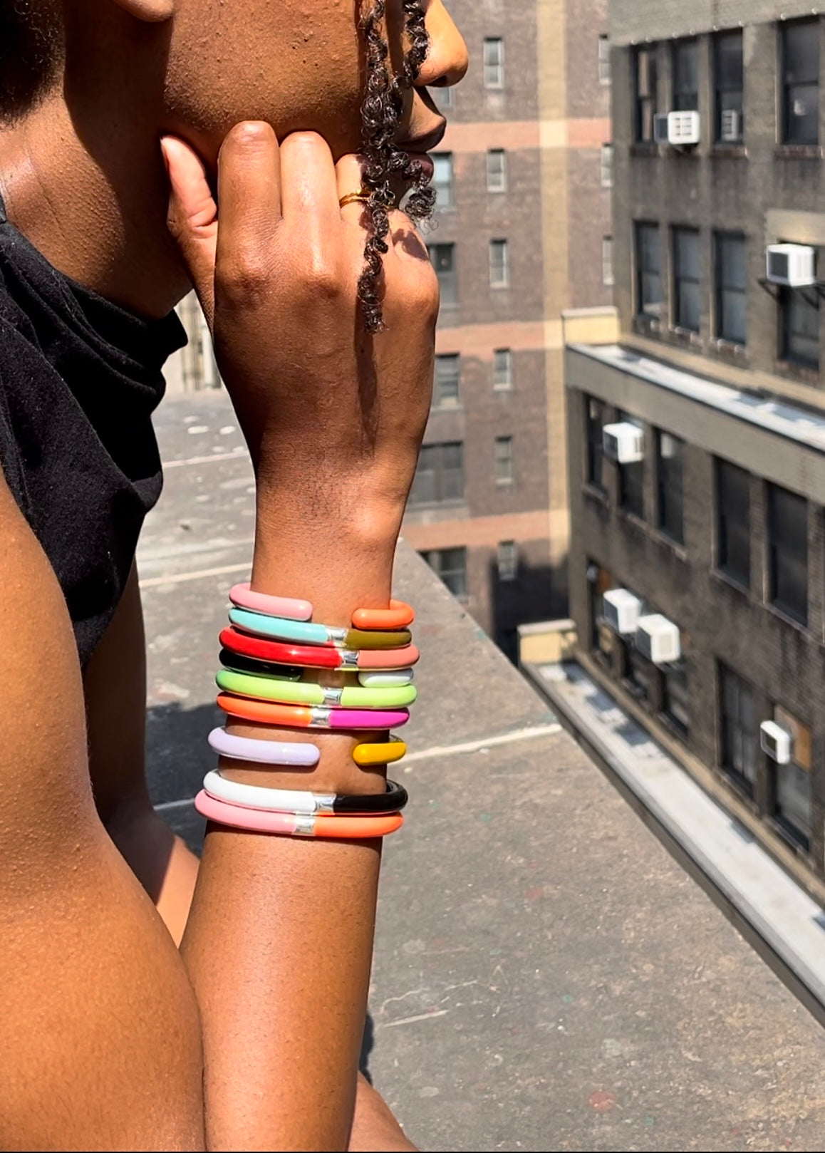 Close up of woman's wrist with many enamel cuff bracelets