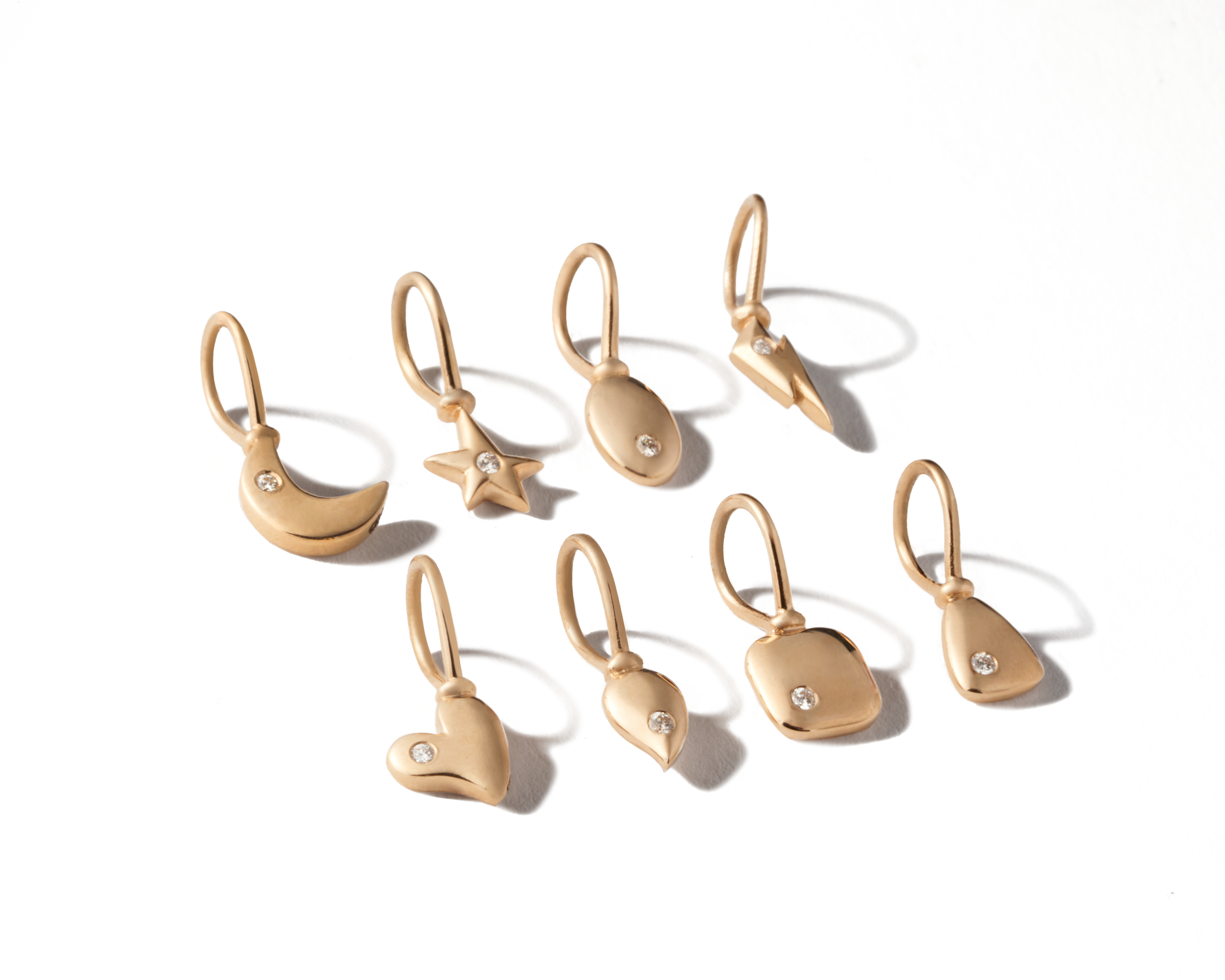 Eight tiny 14k gold charms lined up in two rows
