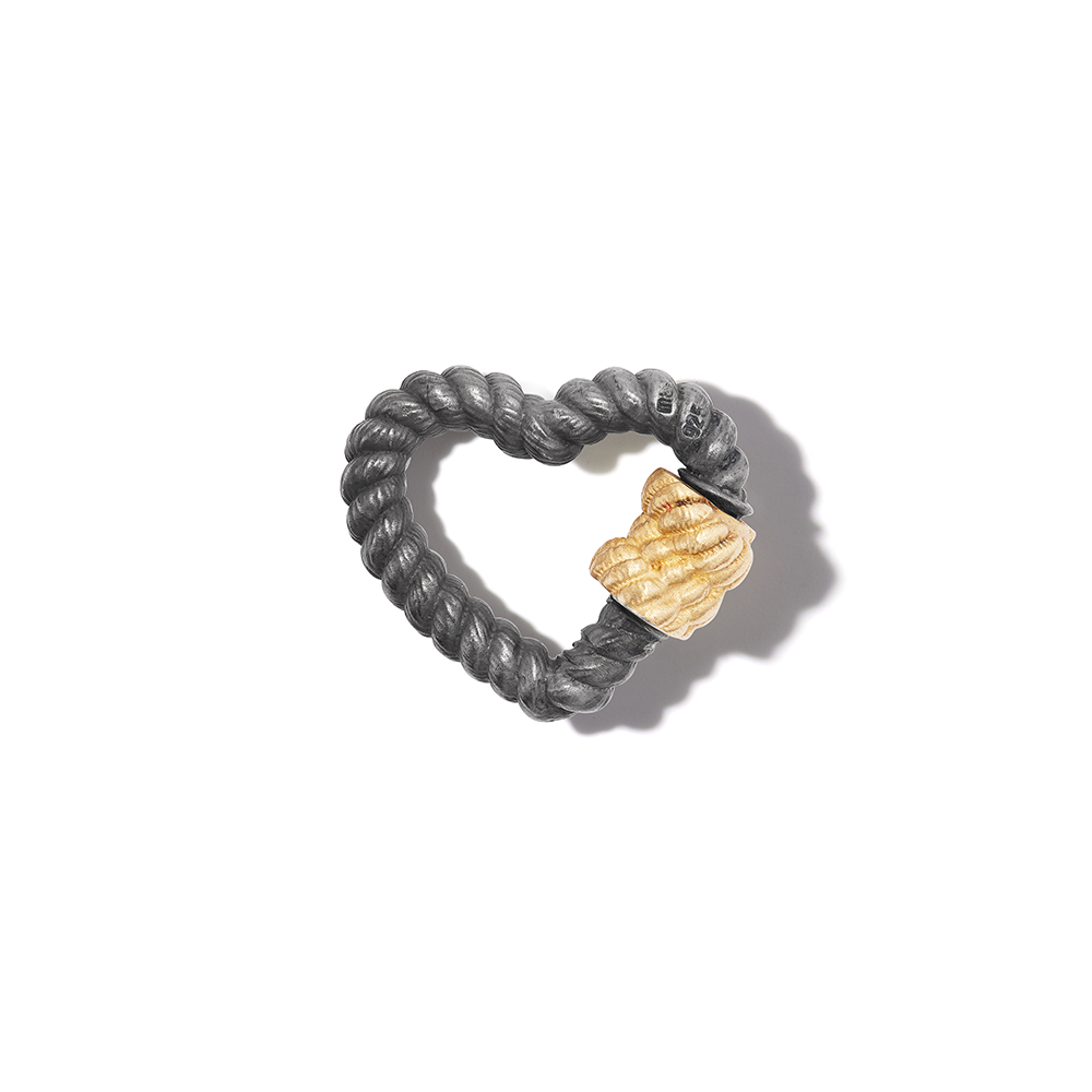 Blackened silver heart lock charm with yellow gold clasp against white backdrop