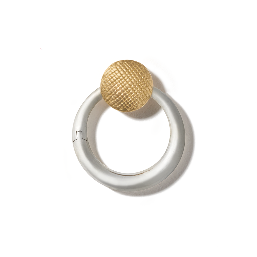 Silver circle charm with yellow gold clasp against white backdrop