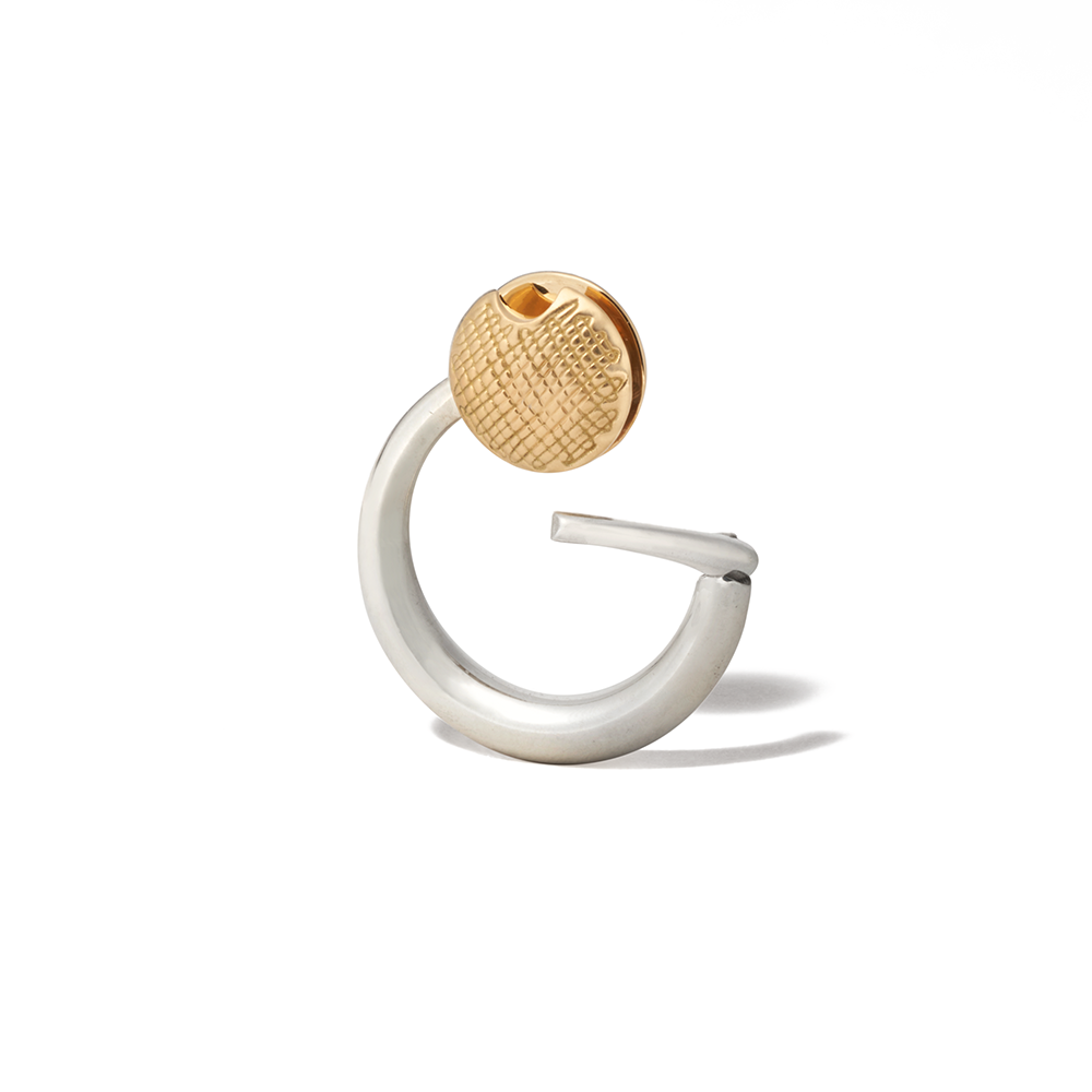 Angled front shot of silver disc charm with yellow gold clasp against white backdrop