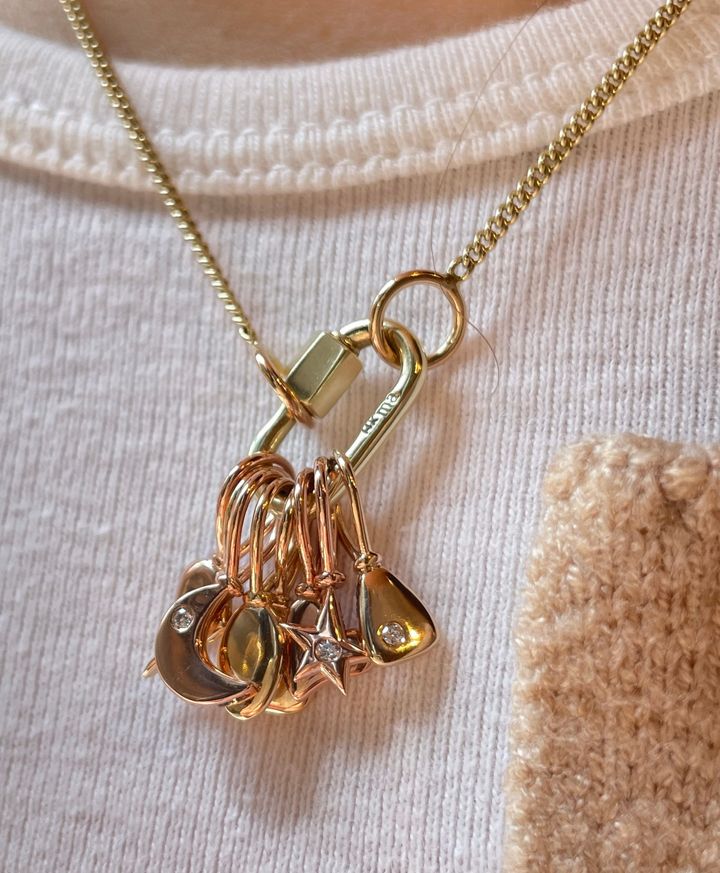 Close up of woman's decolletage wearing necklace with many tiny 14k gold charms