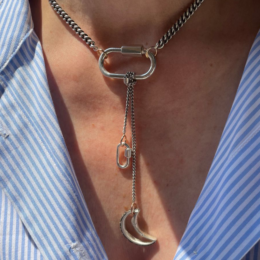 Close up of woman's decolletage wearing silver necklace with lock pendant