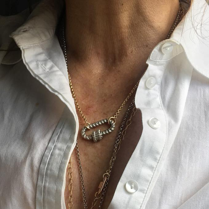 Close up of woman's decolletage wearing necklace with silver twisted lock