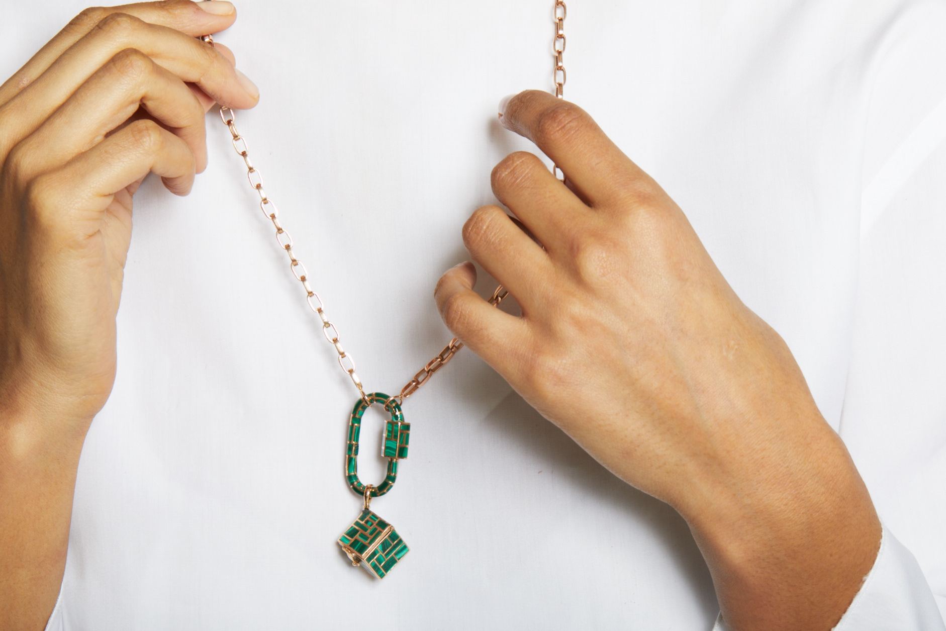 Close up of two hands adjusting rose gold biker chain necklace