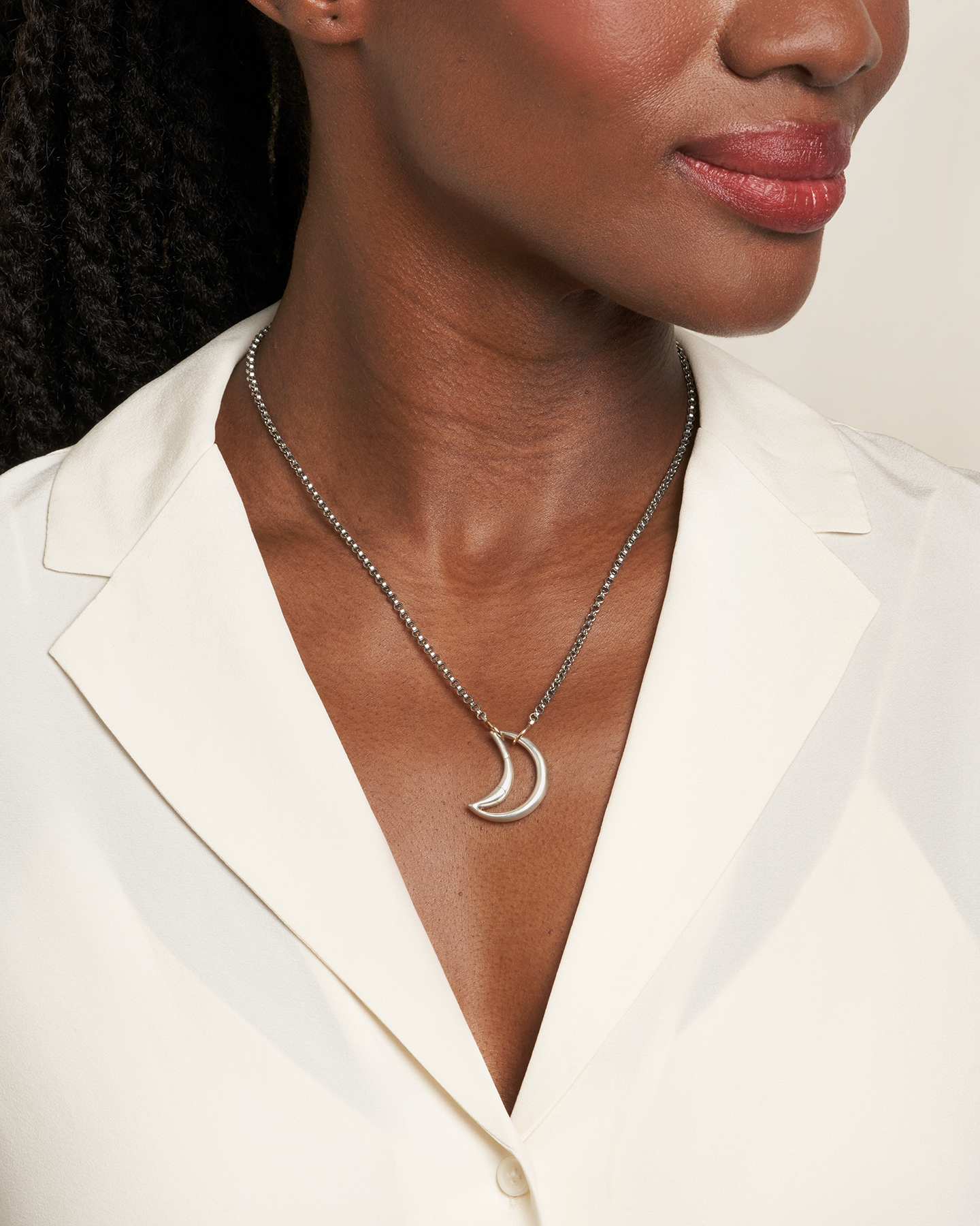 Close up of woman's decolletage wearing necklace with silver moon lock charm