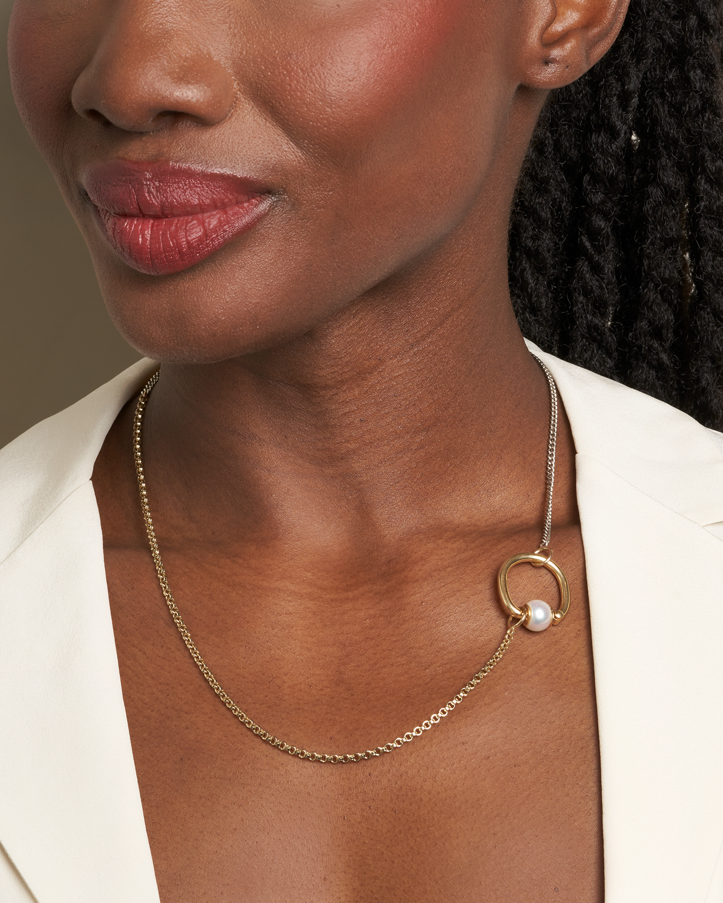 Close up of woman's decolletage with dainty gold and silver necklace and pearl spin ring