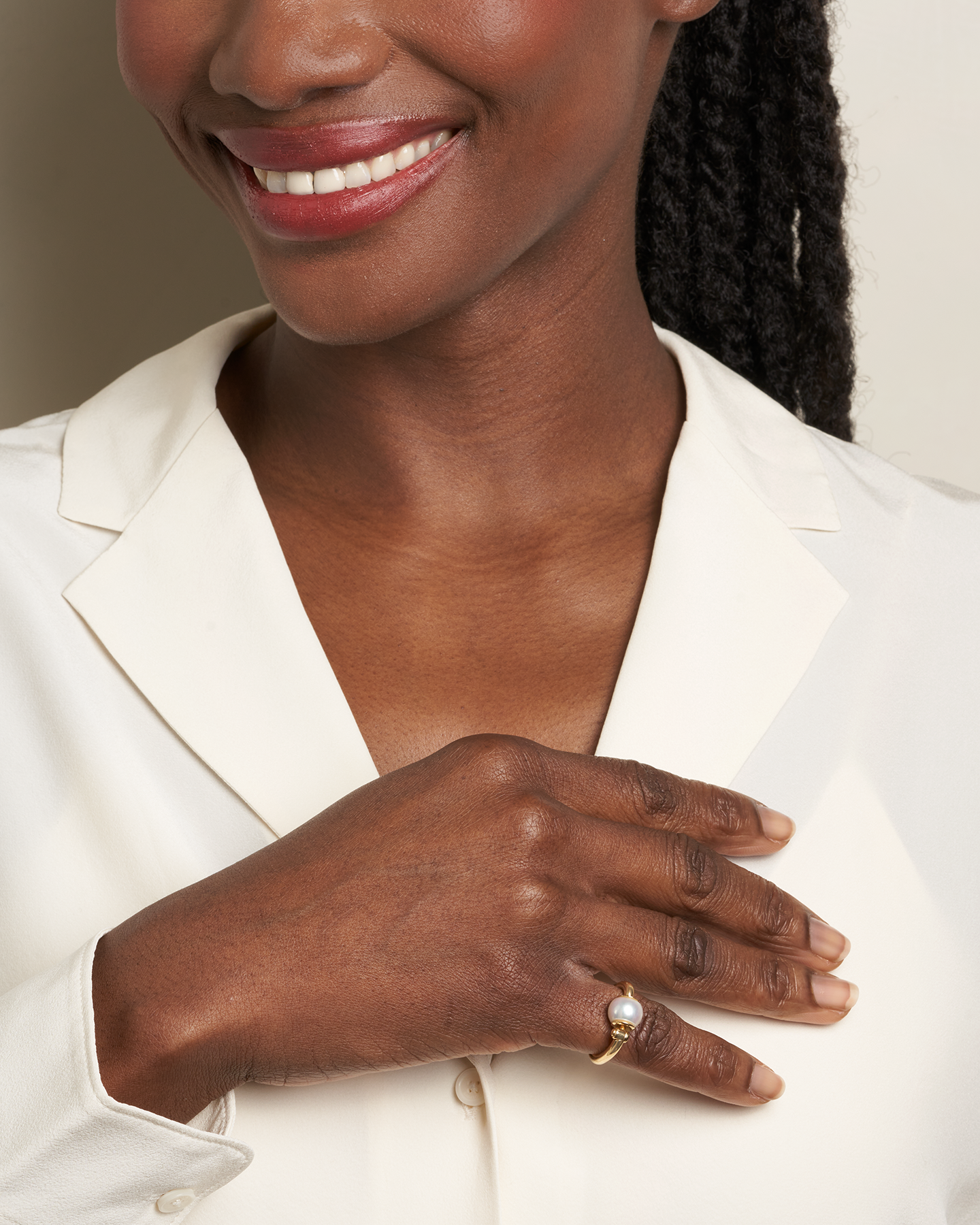 Close up of woman's decolletage with hand across her chest wearing pearl spin ring