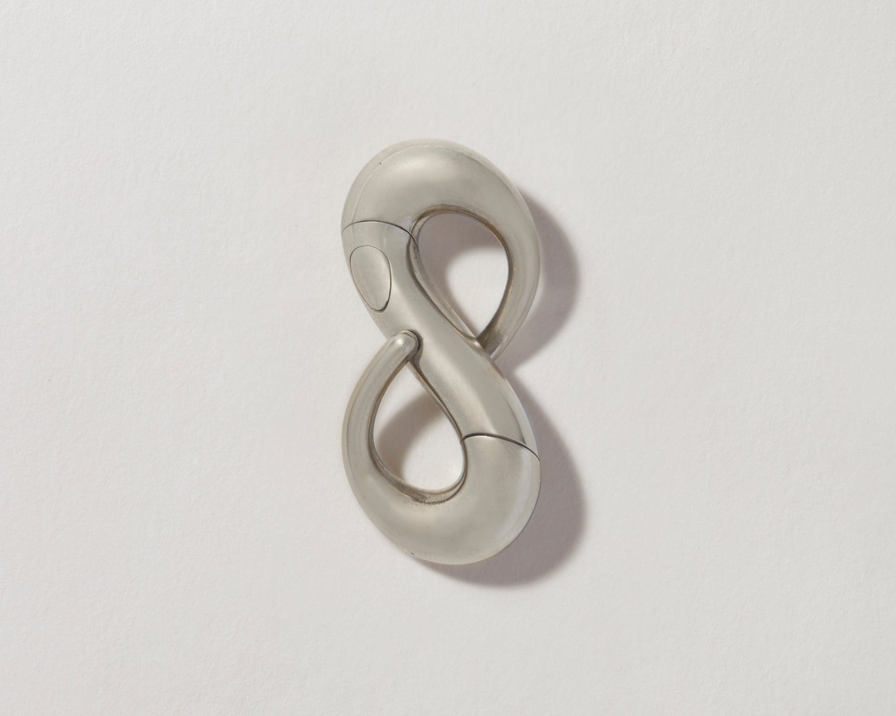 Silver gold infinity lock with clasp closed against gray backdrop