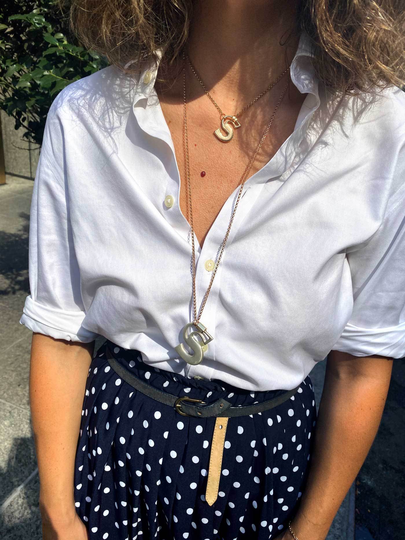 Close up of woman's decolletage wearing two necklaces with S locks