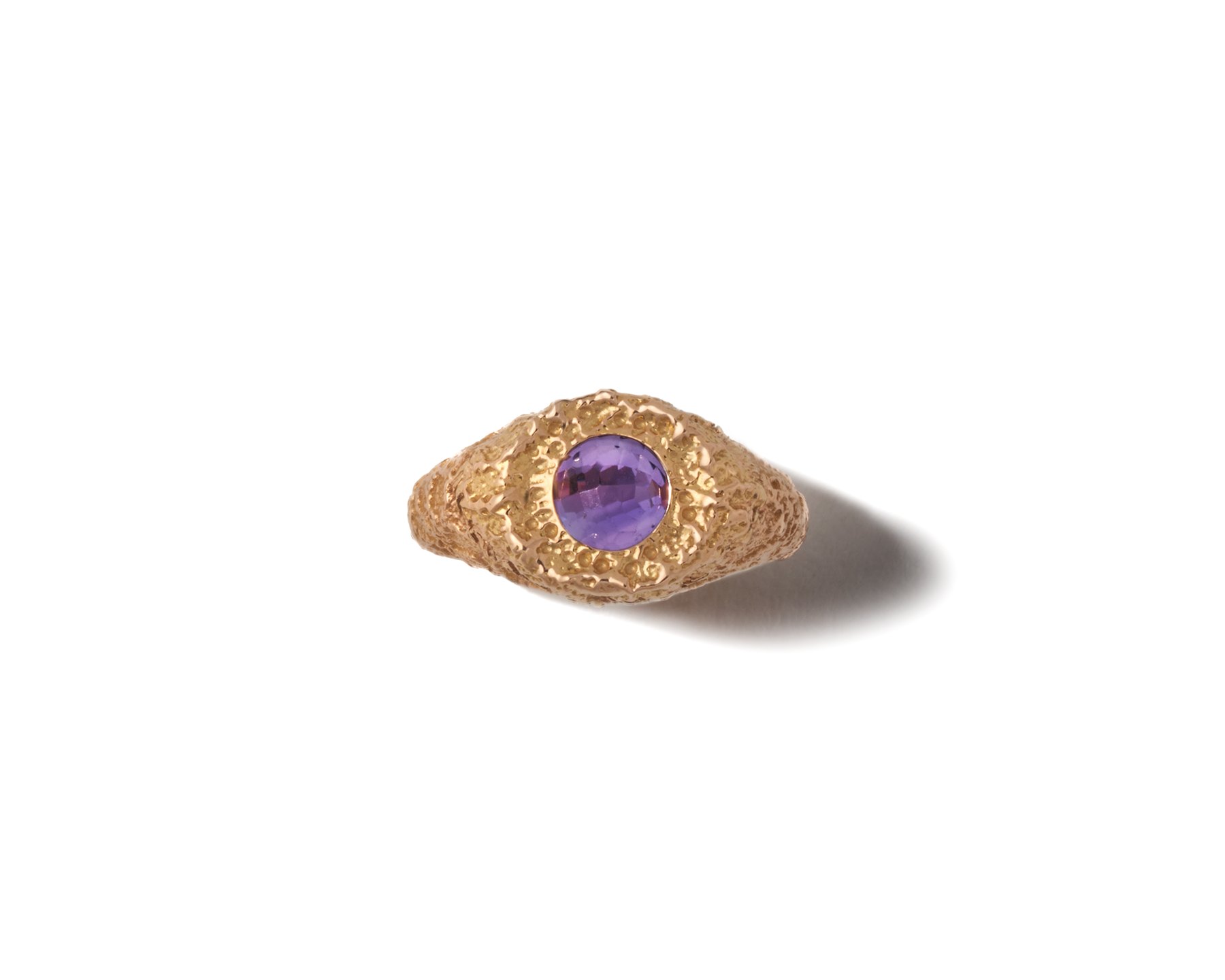 Overhead shot of gold amethyst signet ring against white backdrop