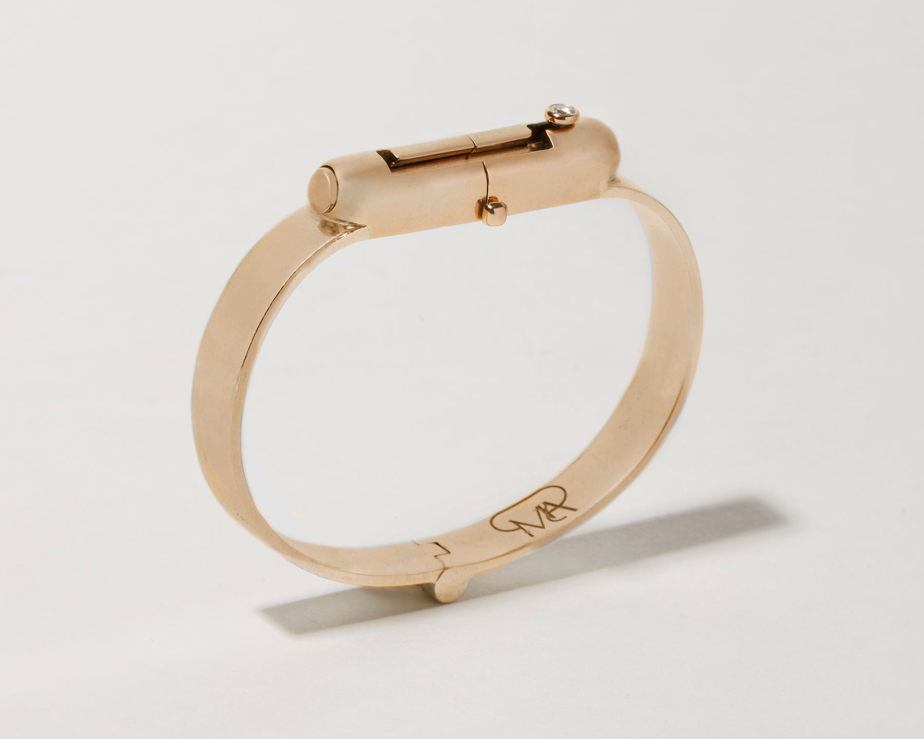 Angled front shot of gold clasp bracelet against white backdrop