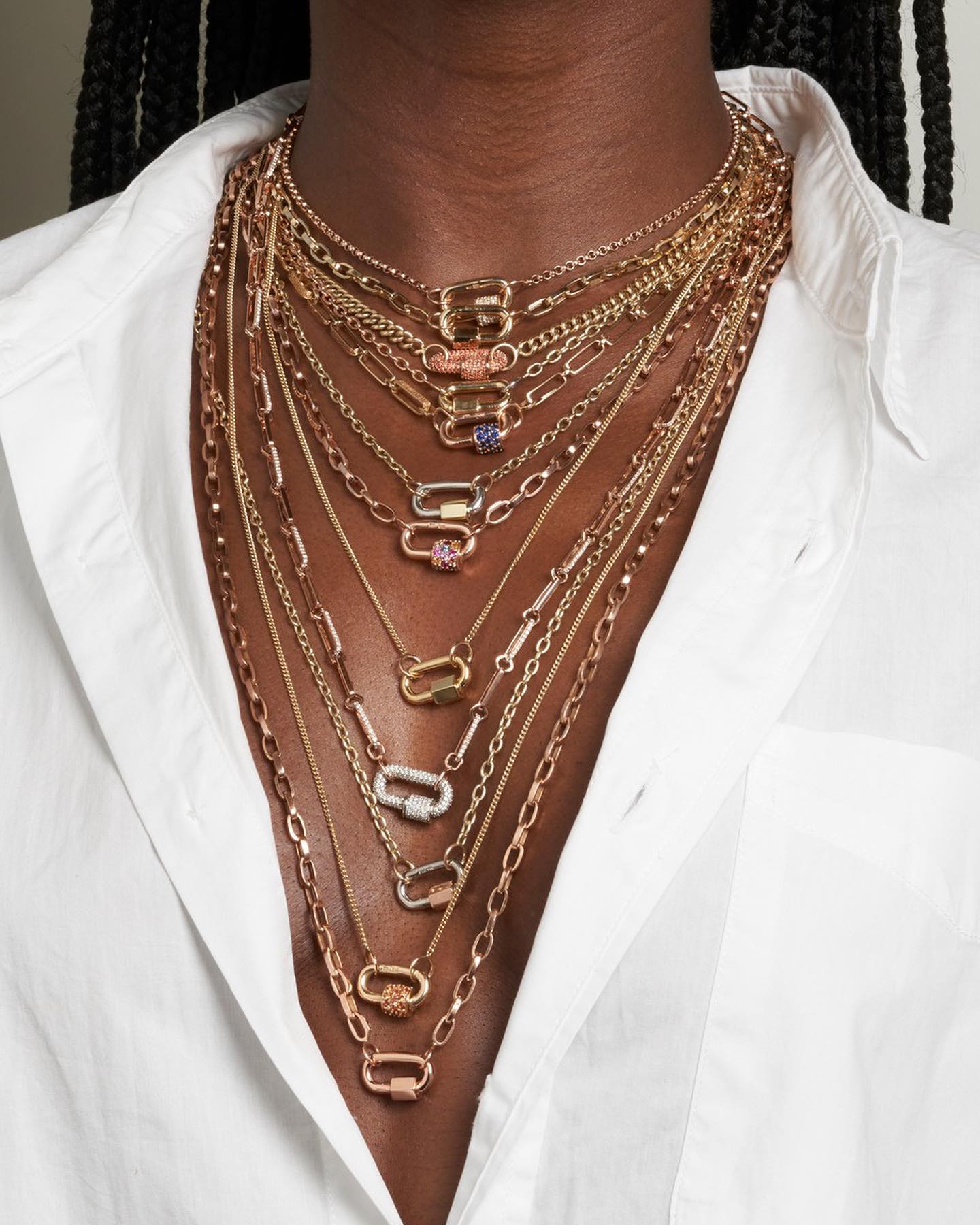 Close up of woman's decolletage wearing many necklaces including very fine gold chain necklace