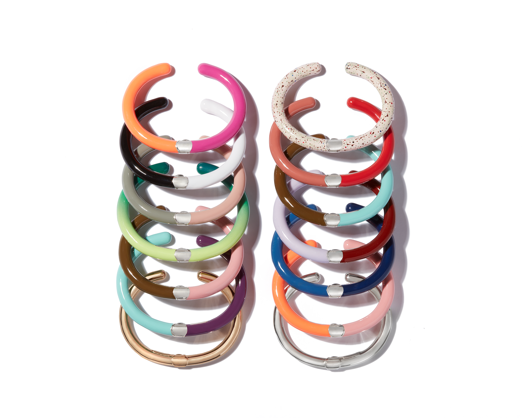 Fourteen different color combination enamel cuff bracelets lined up against white backdrop