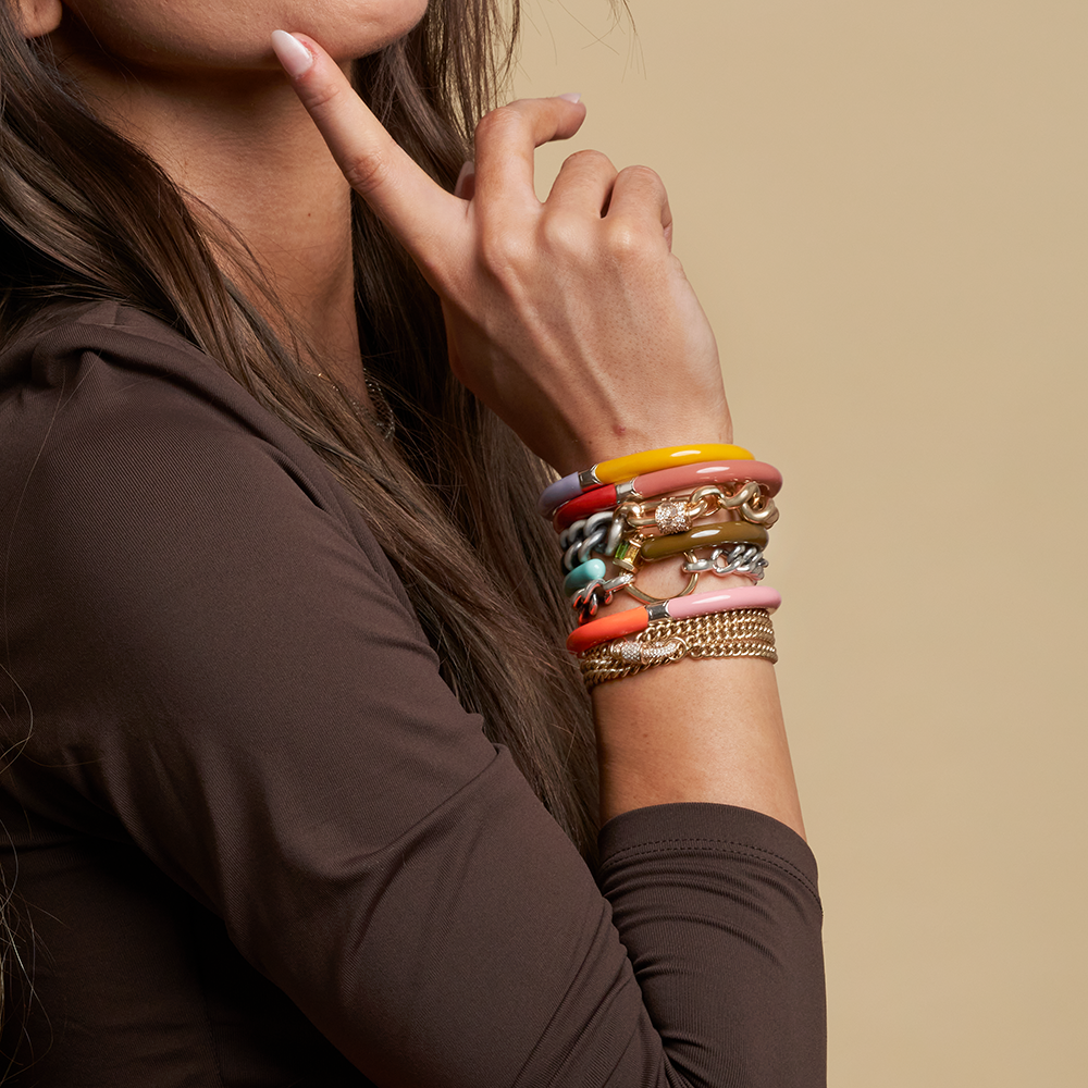 Woman's wrist wearing multiple bracelets including bracelet with diamond baby lock