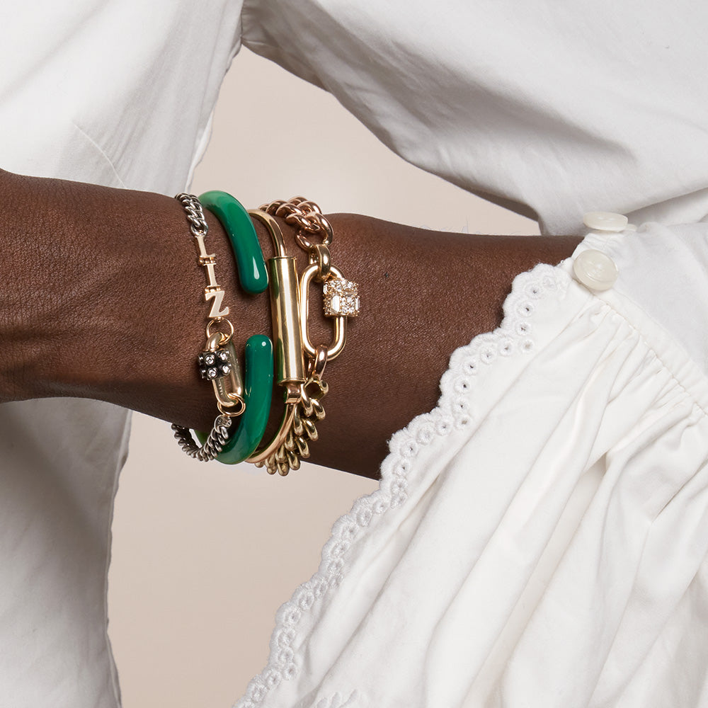 Close up of woman's wrist wearing many bracelets including gold rolling bracelet