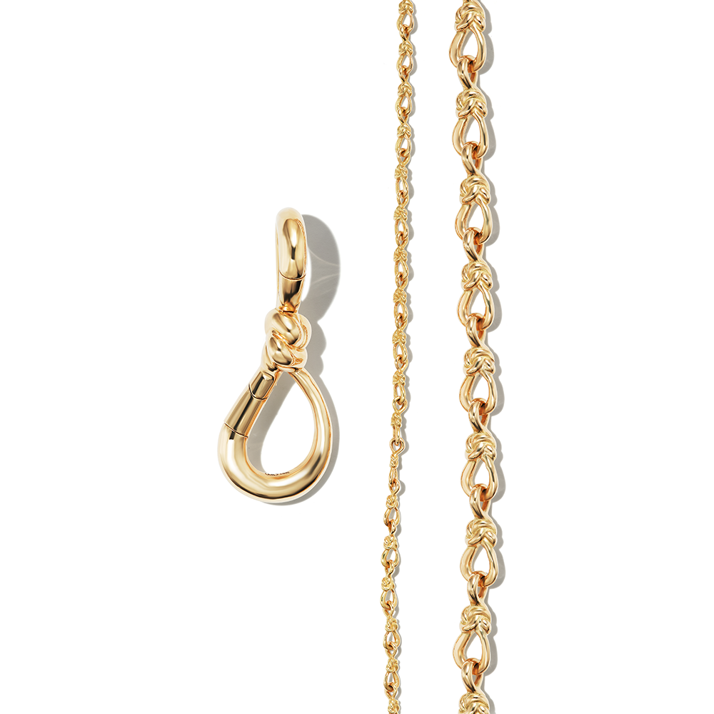 Gold knot charm alongside two gold love chain necklaces