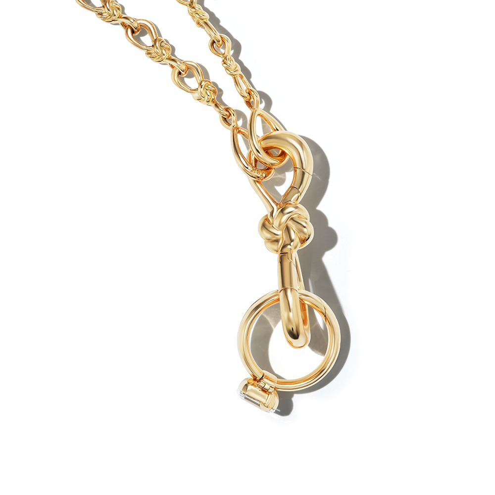Close up of charm and ring on lover's knot necklace gold
