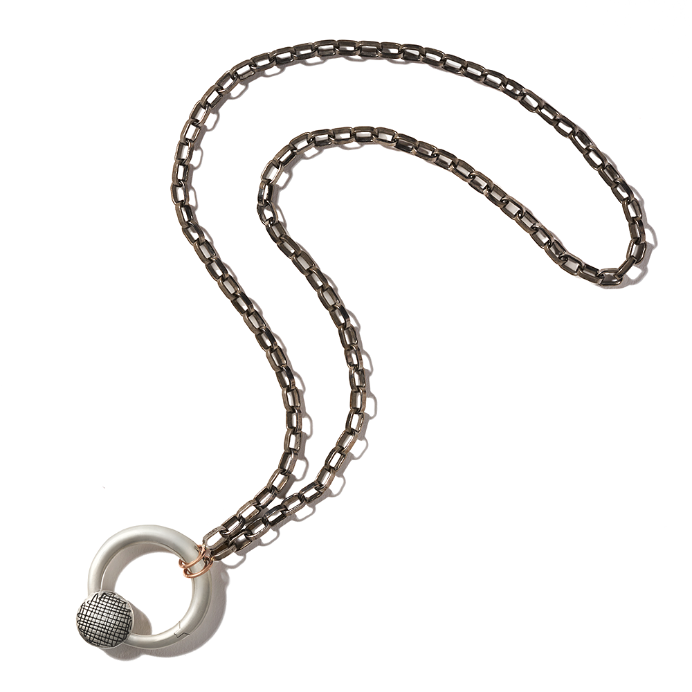 Silver circle charm attached to black chain against white backdrop
