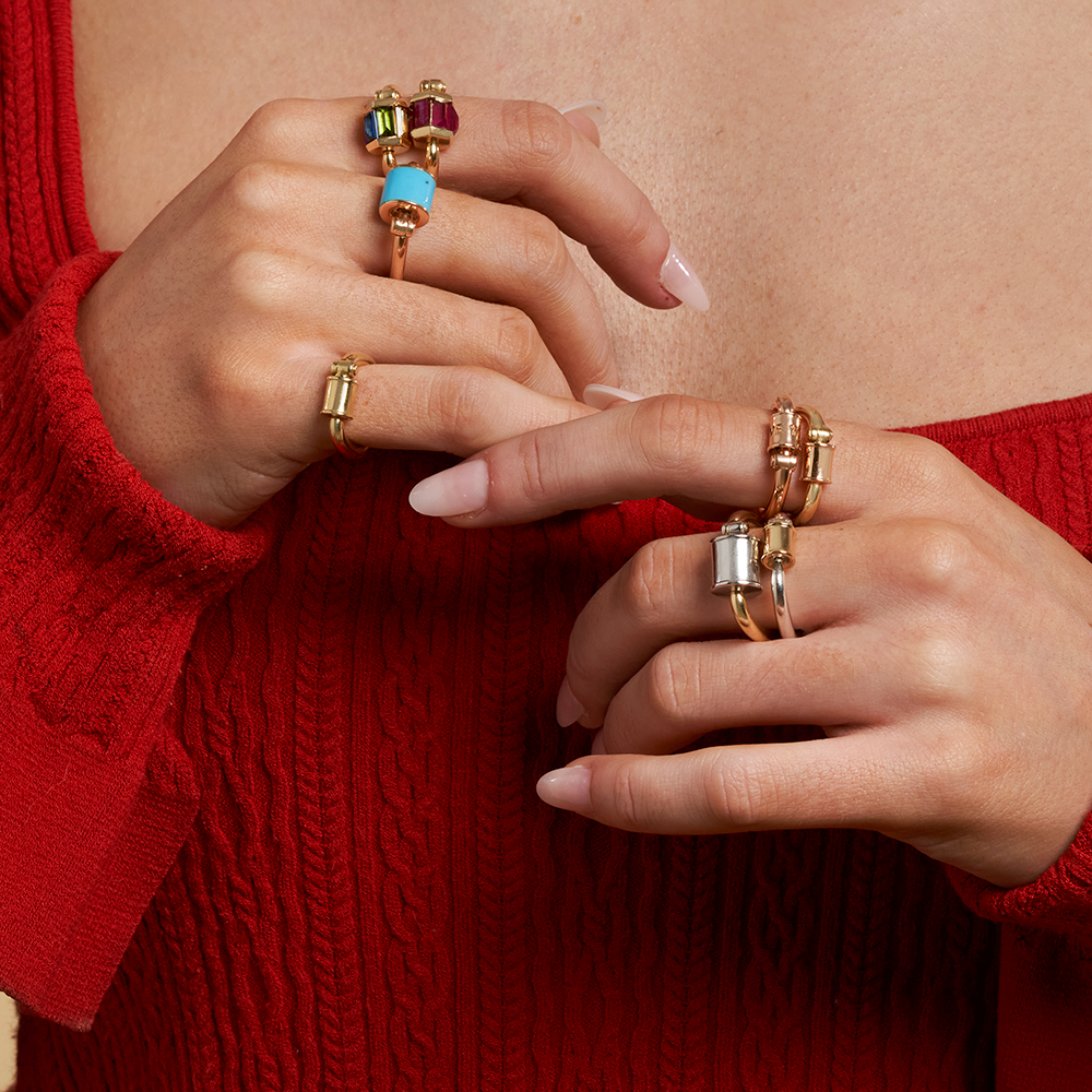 Close up of woman's hands wearing many rings including gold ruby ring with trundle lock