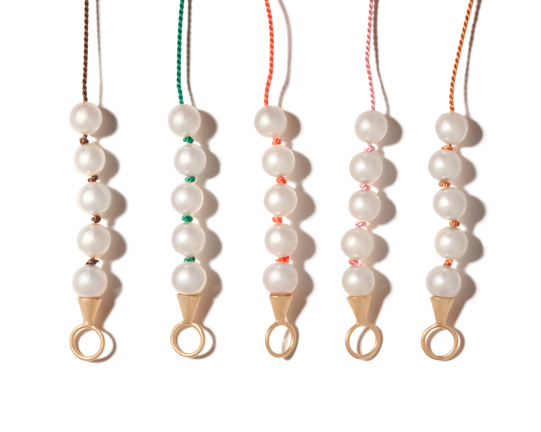 Close up of four custom made pearl necklaces with different color threads
