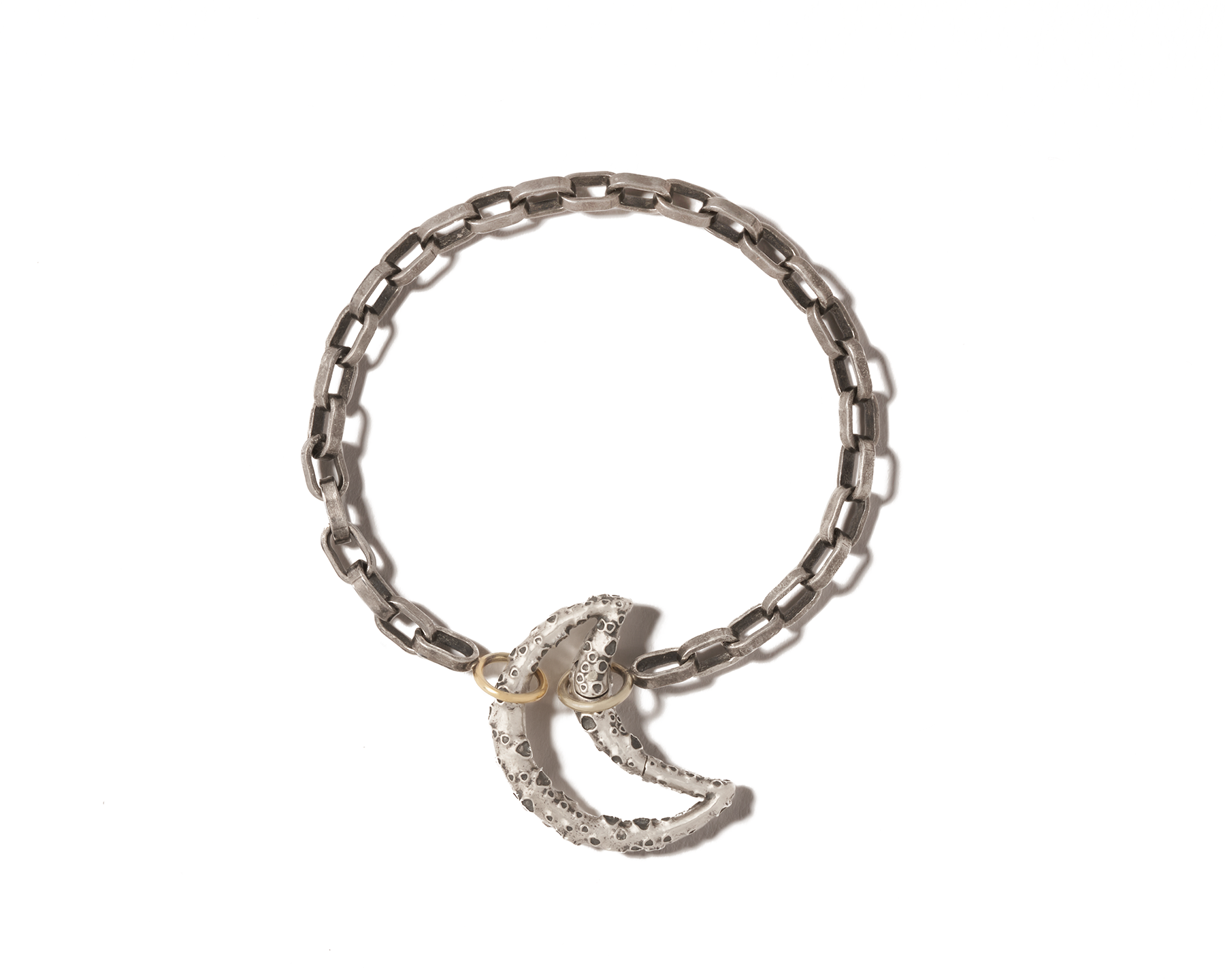 Silver moon charm with cratered surface attached to silver bracelet