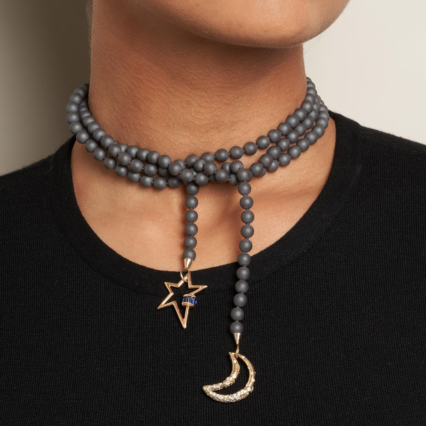 Close up of woman's decolletage wearing necklace with moon charm and star lock charm