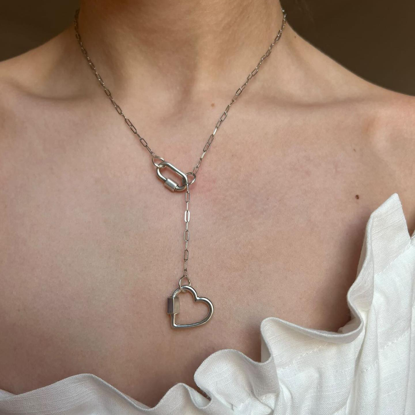 Close up of woman's decolletage wearing necklace with sterling silver heart charm