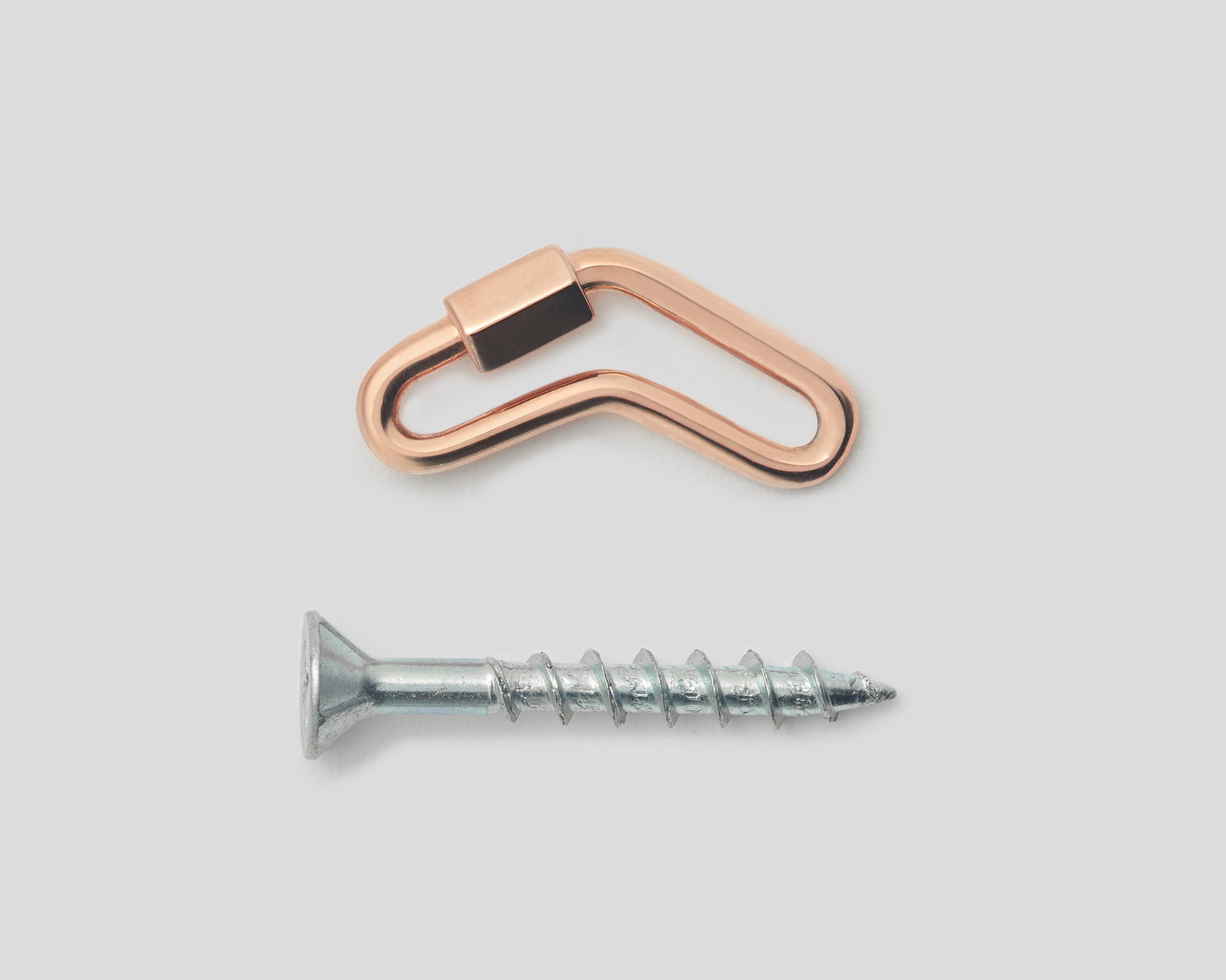 Rose gold boomerang lock charm with closed clasp alongside silver screw