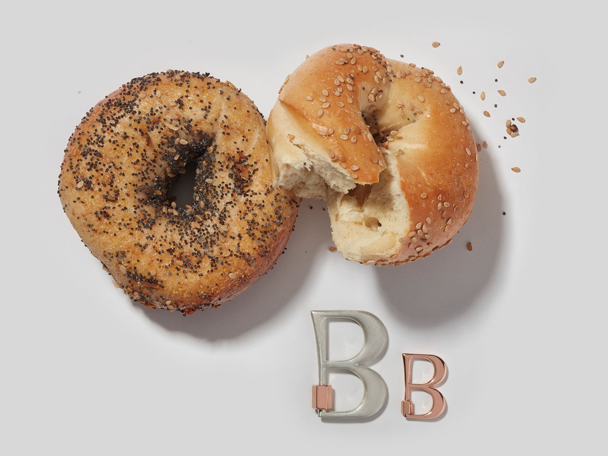 Large silver letter B charm and small rose gold letter B charm alongside two bagels