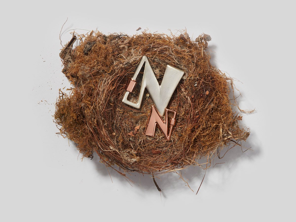 Large silver letter N charm and small rose gold letter N charm inside of nest