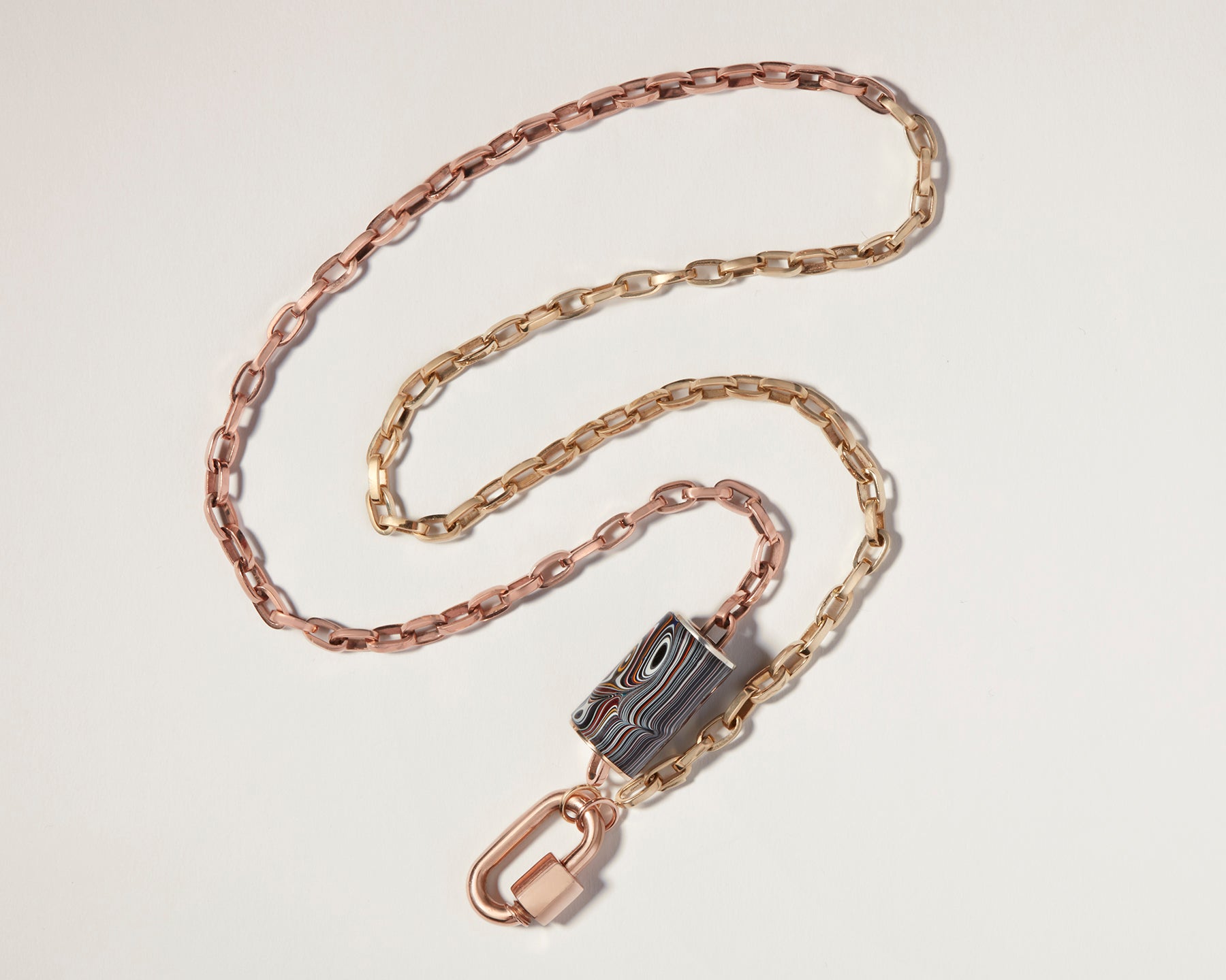 Fordite bead on mixed metal chain against white backdrop