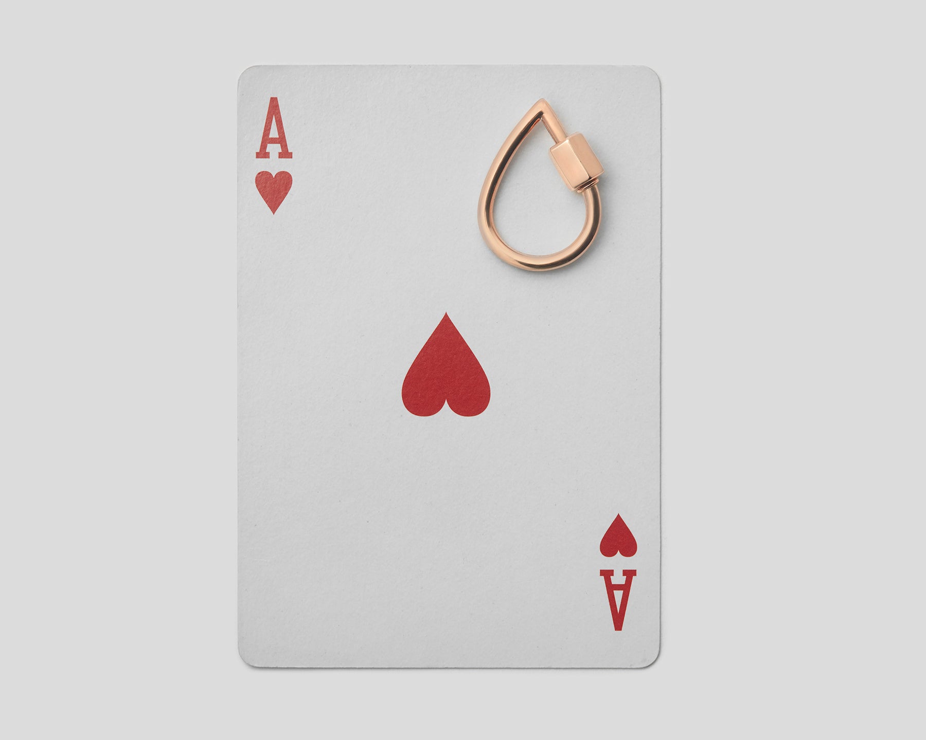 Small rose gold droplock on top of ace of hearts playing card