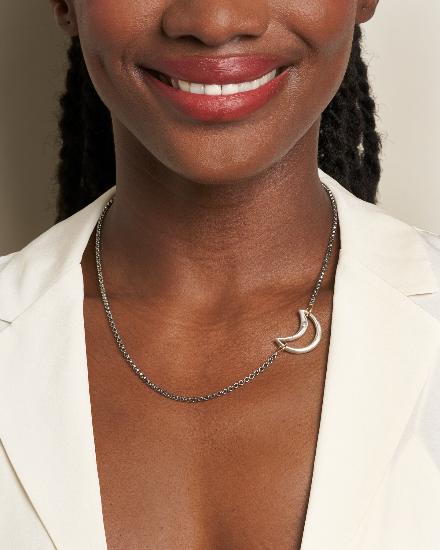 Close up of woman's decolletage and chin wearing necklace with silver moon lock charm