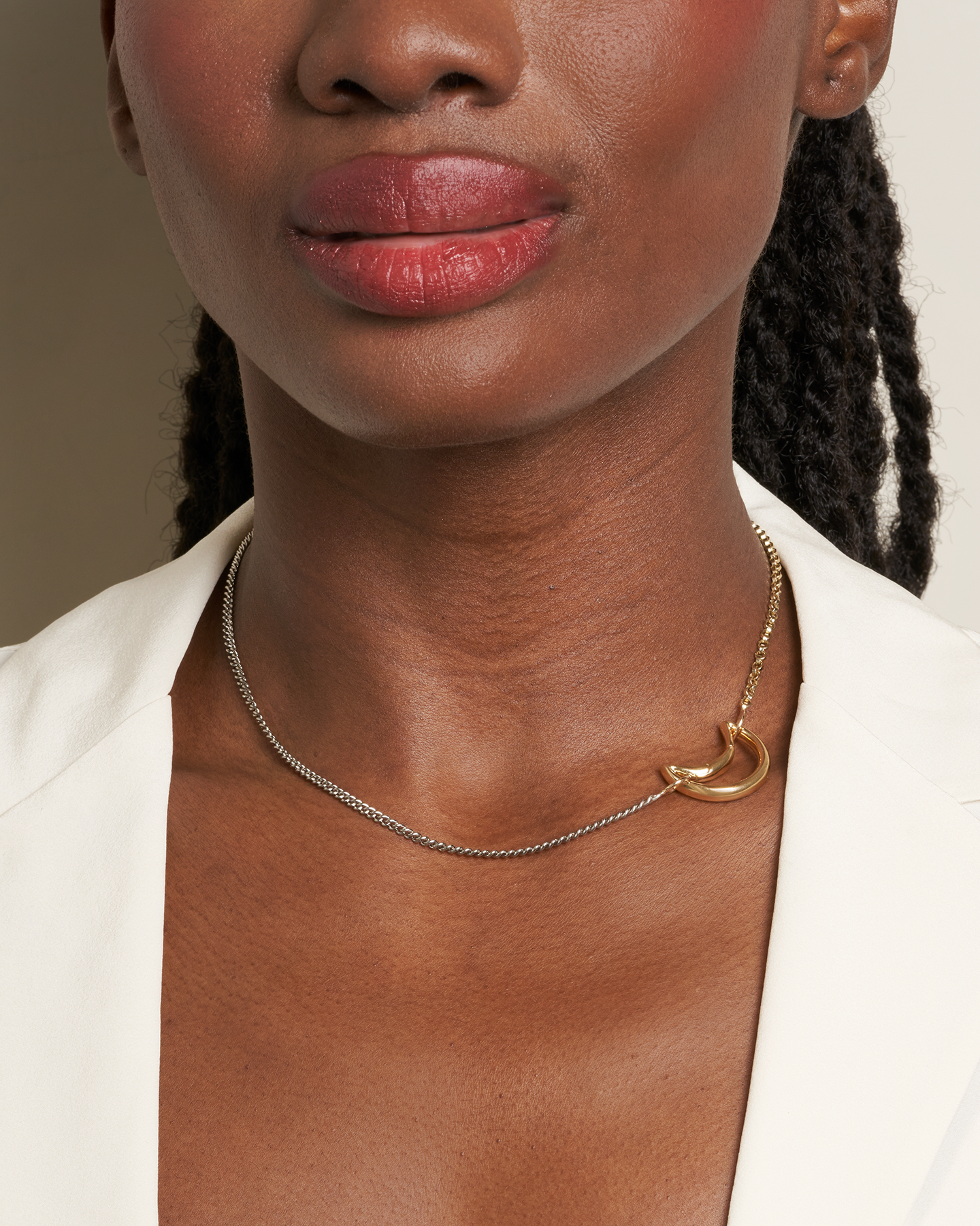 Close up of woman's decolletage wearing necklace with moon lock charm on the right side