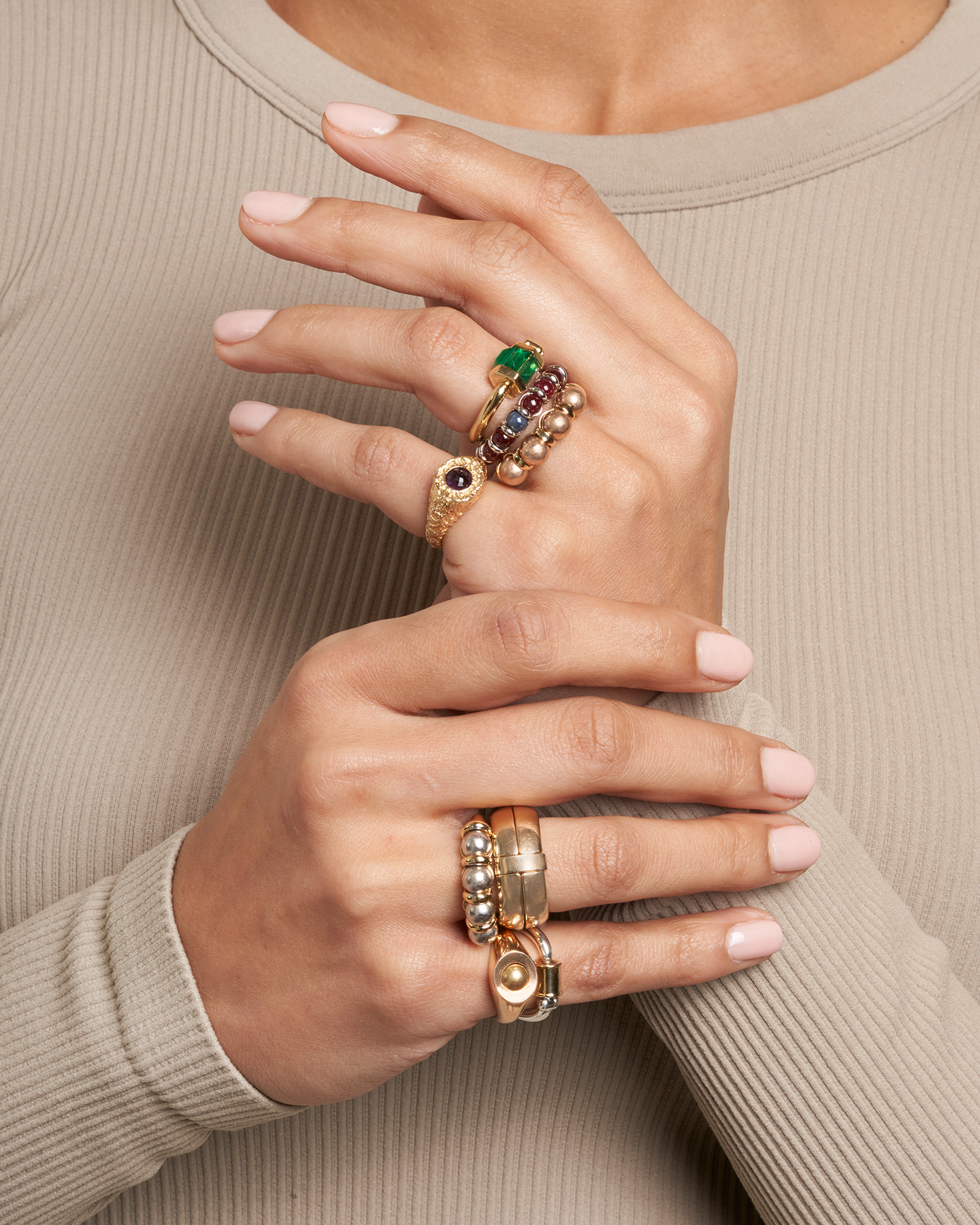 Close up of woman's hands wearing multiple gold and silver sphere rings