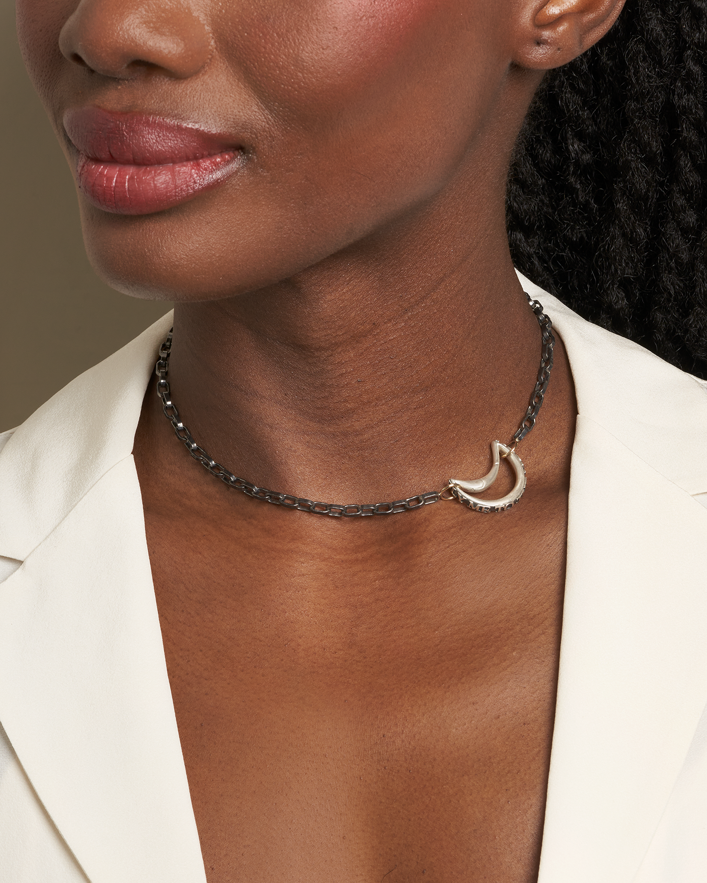 Close up of woman's side-facing decolletage wearing fly me to the moon necklace