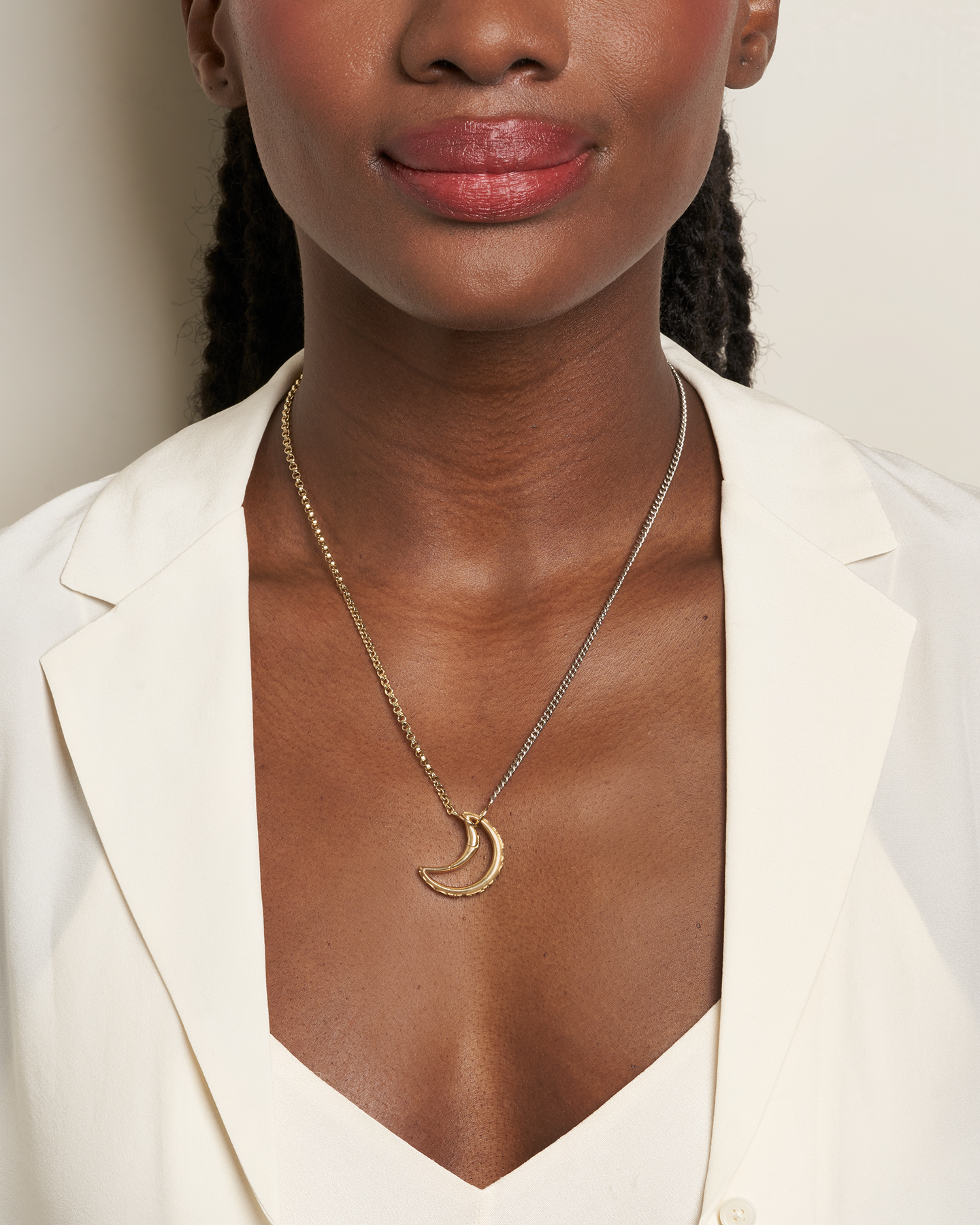 Close up of woman's decolletage wearing gold and silver necklace chain with moon charm