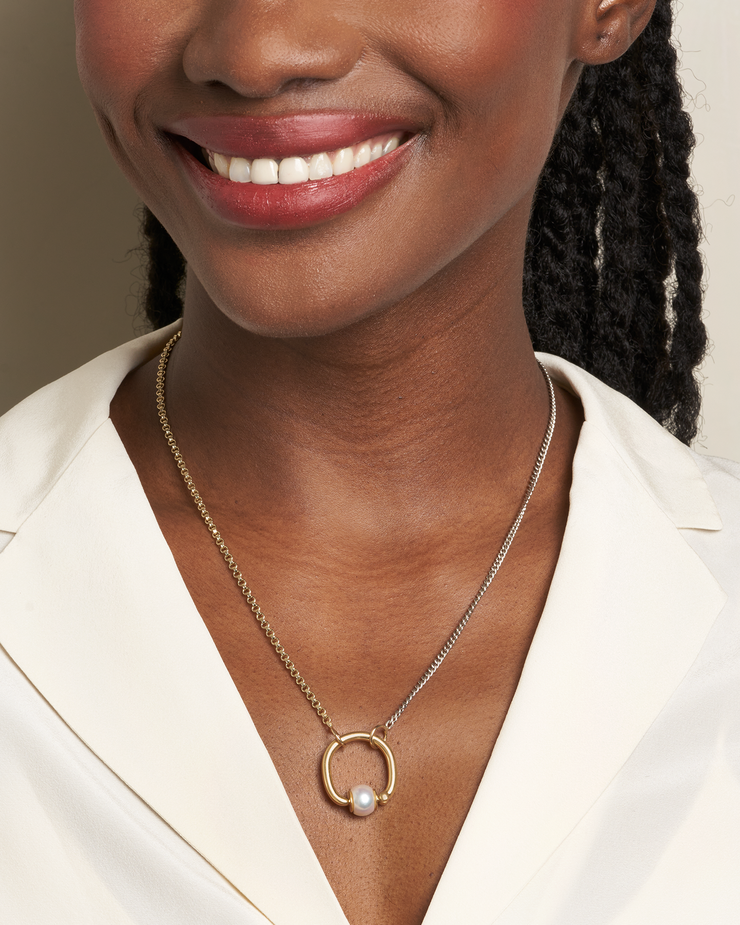 Close up of woman's decolletage with gold necklace with pearl trundle ring on it