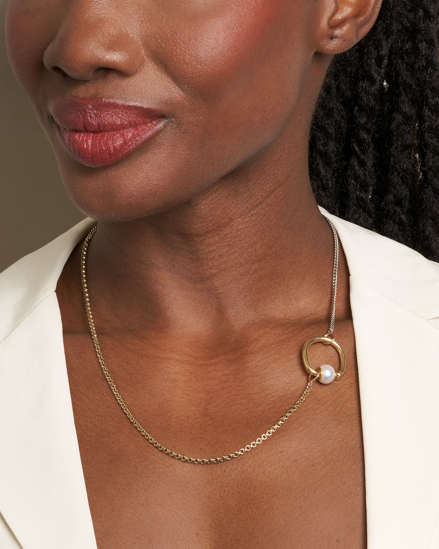 Close up of woman's decolletage with dainty gold and silver necklace and pearl spin ring 