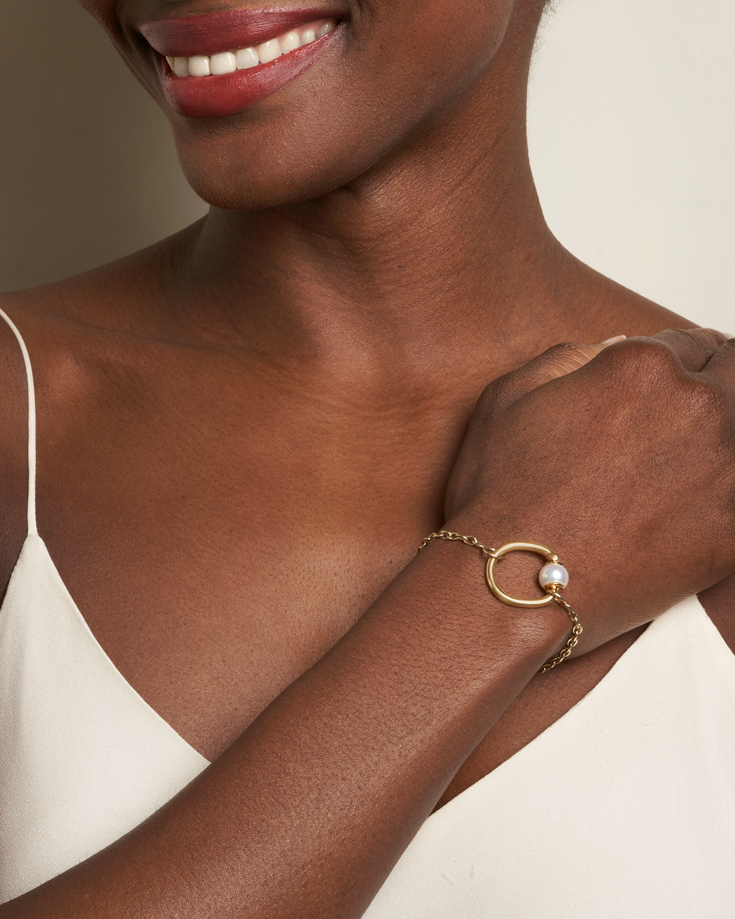 Close up of woman's decolletage with hand across her chest wearing bracelet with trundle pearl ring