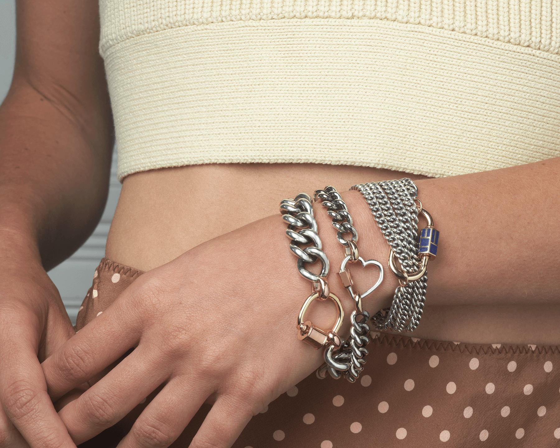 Close up of woman's wrist wearing multiple bracelets including mixed metal chain bracelet