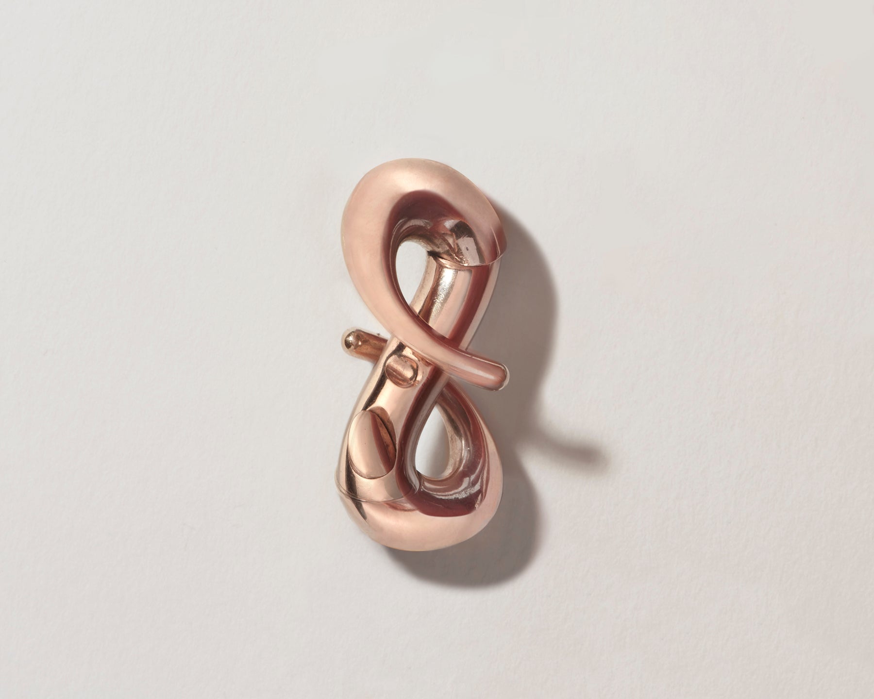 Rose gold infinity lock with clasp open against gray backdrop