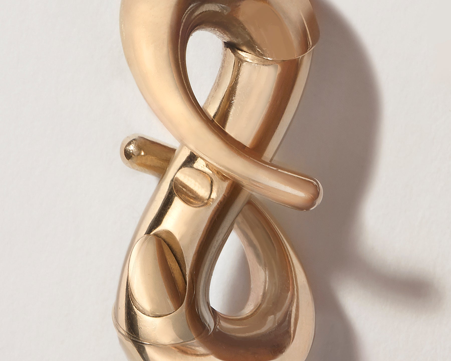 Close up of gold infinity lock with clasp open against gray backdrop