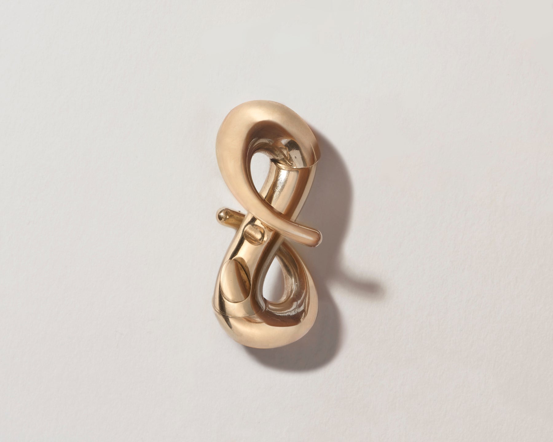 Gold infinity lock with clasp open against gray backdrop